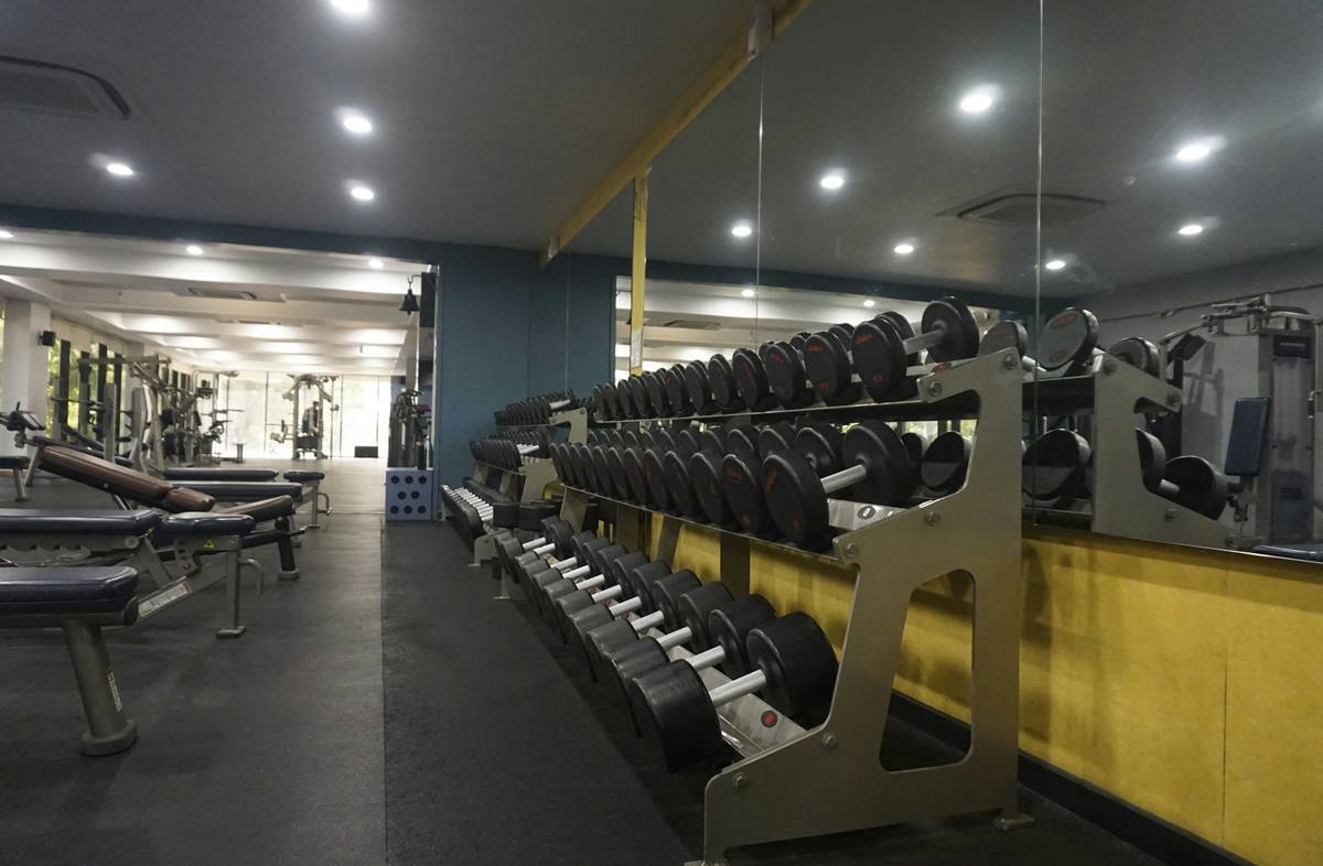 Side-by-side comparison: left shows a dim home gym with poor overhead lighting casting shadows; right shows the same space with 5000K LED strip lights under shelves and along baseboards providing even, shadow-free illumination.